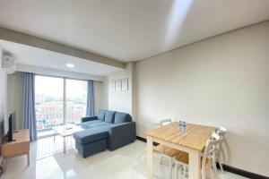 a living room with a blue couch and a table at Spacious 2BR Apartment at El Royale near BIP By Travelio in Bandung