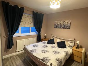 a bedroom with a bed with black curtains and a window at NKN cosy maisonette close to Dartford train station, free parking, food, shopping in Kent +24 photos