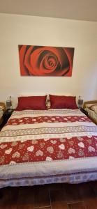 a bed with a red comforter and a painting on the wall at I Sei Petali Apartment in Capo di Ponte