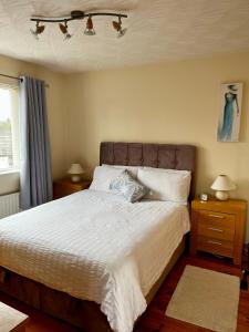 a bedroom with a large bed with white sheets and pillows at Bush Lodge Bushmills in Bushmills