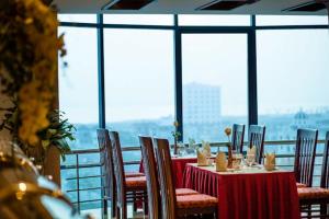 a dining room with tables and chairs and windows at Kenny Hotel Ha Long in Ha Long