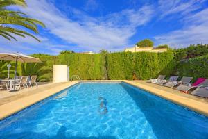 a large swimming pool with chairs and a hedge at Villa Carola - PlusHolidays in Ifach