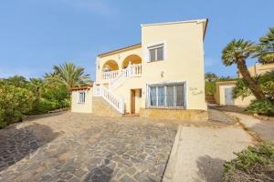 a large white house with palm trees and a driveway at Villa Carola - PlusHolidays in Ifach