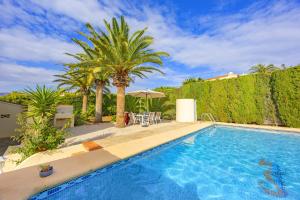 a swimming pool with palm trees in a yard at Villa Carola - PlusHolidays in Ifach