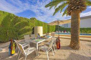 a table with chairs and an umbrella next to a palm tree at Villa Carola - PlusHolidays in Ifach +39 photos