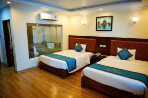a hotel room with two beds and a mirror at Kenny Hotel Ha Long in Ha Long
