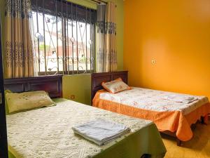 two beds in a room with a window at KAZ Appartment in Kampala