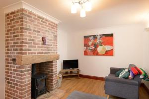 sala de estar con chimenea de ladrillo y sofá en Wood Farm Dairy, en Beccles