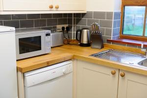 Una encimera de cocina con un microondas y un fregadero. en Wood Farm Dairy, en Beccles