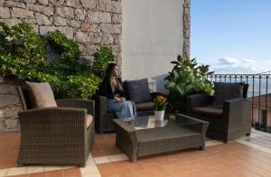 a woman sitting on a couch on a patio at Hotel Bia Maore in Baunei