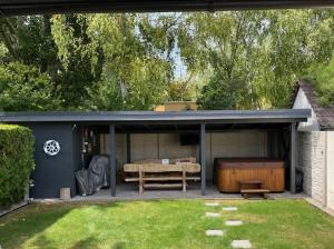 a covered patio with a table and a tub at Te meg Én Gárdony vendégház in Gárdony