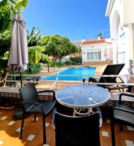 a patio with a table and chairs and a pool at El Jardin BeNerja in Nerja
