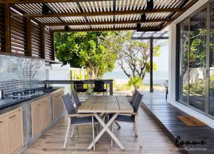 an outdoor kitchen with a wooden table and chairs at lomme Private Beach House in Cha Am