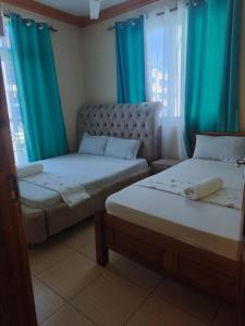 two beds in a room with blue curtains at Mtwapa luxury apartment in Mombasa