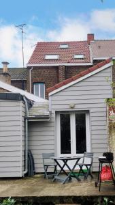a picnic table and two chairs in front of a house at Le petit refuge 28m2 2 personnes avec extérieur in Denain
