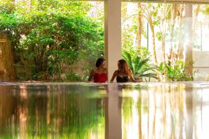 two women sitting next to a swimming pool at Port Benidorm Hotel & Spa 4* Sup in Benidorm