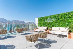 a patio with chairs and tables and a green wall at Port Benidorm Hotel & Spa 4* Sup in Benidorm