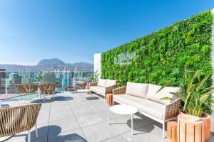 a rooftop patio with furniture and a green wall at Port Benidorm Hotel & Spa 4* Sup in Benidorm