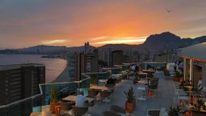 a balcony with tables and chairs and a sunset at Port Benidorm Hotel & Spa 4* Sup in Benidorm