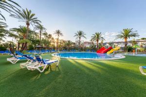 Un resort con piscina con sillas y palmeras. en Port Denia, en Denia
