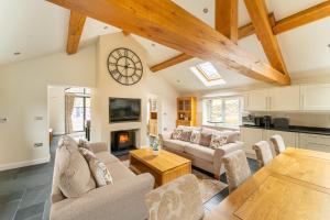 a living room with couches and a table and a fireplace at Lakes Cottage in Backbarrow