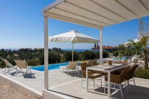 a patio with a table and chairs and an umbrella at Nikiti Dream Villas in Nikiti