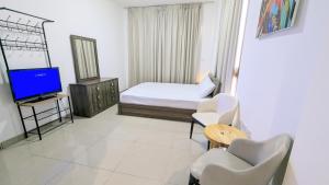 a bedroom with a bed and a tv and chairs at Dragon Premium Homes in Dubai