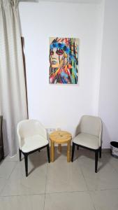 two chairs and a table in a room with a painting at Dragon Premium Homes in Dubai