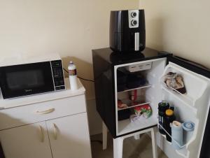 een kleine koelkast met de deur open naast een magnetron bij Casa próximo centro de eventos com ar condicionado in Fortaleza +8 foto's