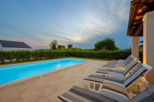 a row of lounge chairs next to a swimming pool at Villa RE by Istrialux in Svetvinčenat
