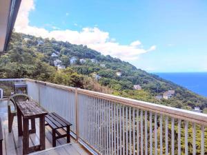 balcón con banco y vistas al océano en 絶景温泉付き別荘, en Higashiizu