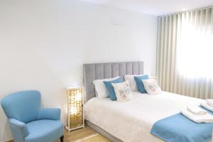 a bedroom with a bed and a blue chair at Dunas Ria Apartment T2 in Gafanha da Encarnação