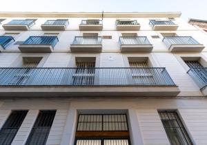 a tall white building with windows and bars at Apartamentos Cervantes 17 in Seville