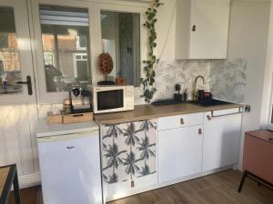a kitchen with white cabinets and a microwave at Botanique in Den Hoorn