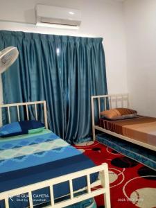two beds in a room with green curtains at Sri Manik Guest House Tanjung Karang in Tanjung Karang