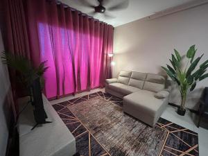 a living room with a couch and a pink curtain at Atenza Homestay Residensi KLIA Condominium, 4 bedrooms 3 bathrooms , Near KLIA and Sepang F1 in Nilai