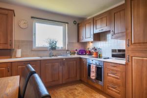 Una cocina con armarios de madera y una ventana. en The Haven, en Stonehaven