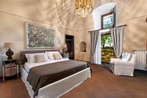 a bedroom with a bed and a chair and a chandelier at Il Pozzillo Maison in Massa Lubrense +32 photos
