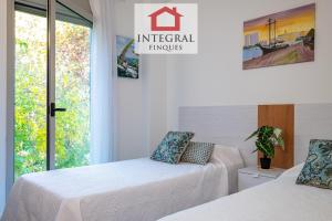 2 Betten in einem Zimmer mit einem Schild, das kaiserliche Umarmungen liest in der Unterkunft El Coralí Apartament Palamós in Palamós + 22 Fotos