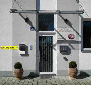 a building with two potted plants in front of a door at Schirmer`s Hotelino in Röhrmoos +1 photo