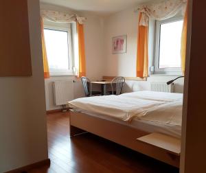 a bedroom with a bed and a table and two windows at Schirmer`s Hotelino in Röhrmoos +4 photos