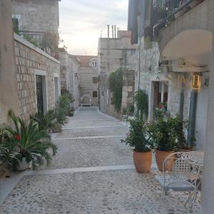 un callejón con macetas y un banco en San Marco Makarska, en Makarska