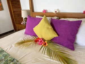 a bed with purple and yellow pillows and a plant on it at Village des Iles in Praslin