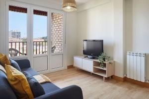 a living room with a blue couch and a tv at EARRA - Amalur - 8 min de la playa, 5 min centro in Zarautz