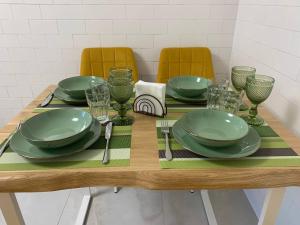 a wooden table with green plates and glasses on it at Апартаменти в ЖК Тріумф in Lutsk