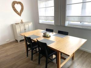 a wooden dining room table with chairs and a heart on the wall at Alfazema Alojamento Local in Angra do Heroísmo
