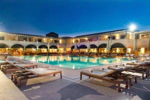 a large swimming pool with lounge chairs and a building at Apart Daire in Didim