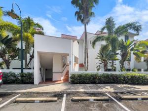 a white house with palm trees in front of it at Rio Mar Village Beach Apt for Families and Groups in Rio Grande