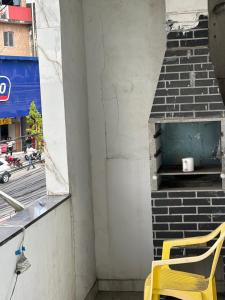a yellow chair sitting on a balcony with a brick oven at Casa do love in Salvador