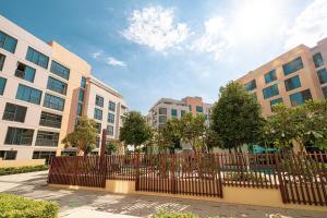 シャルジャにあるLuxury Huge 1BR apartment With Private Garden in Uptown Al Zahiaの木々のある建物の前にあるフェンス